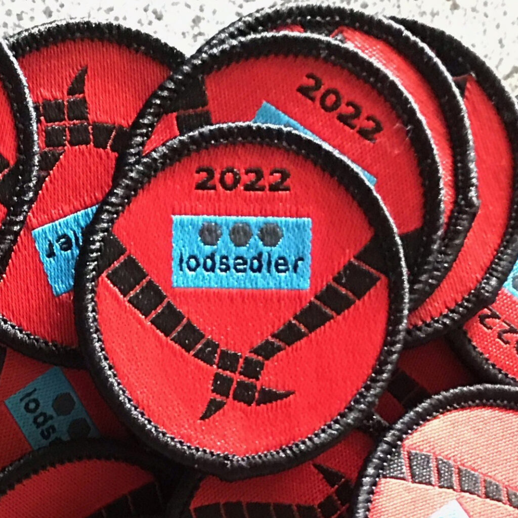 Lodsedel mærke 2022, rød baggrund, sort tekst, blå lodsedel.